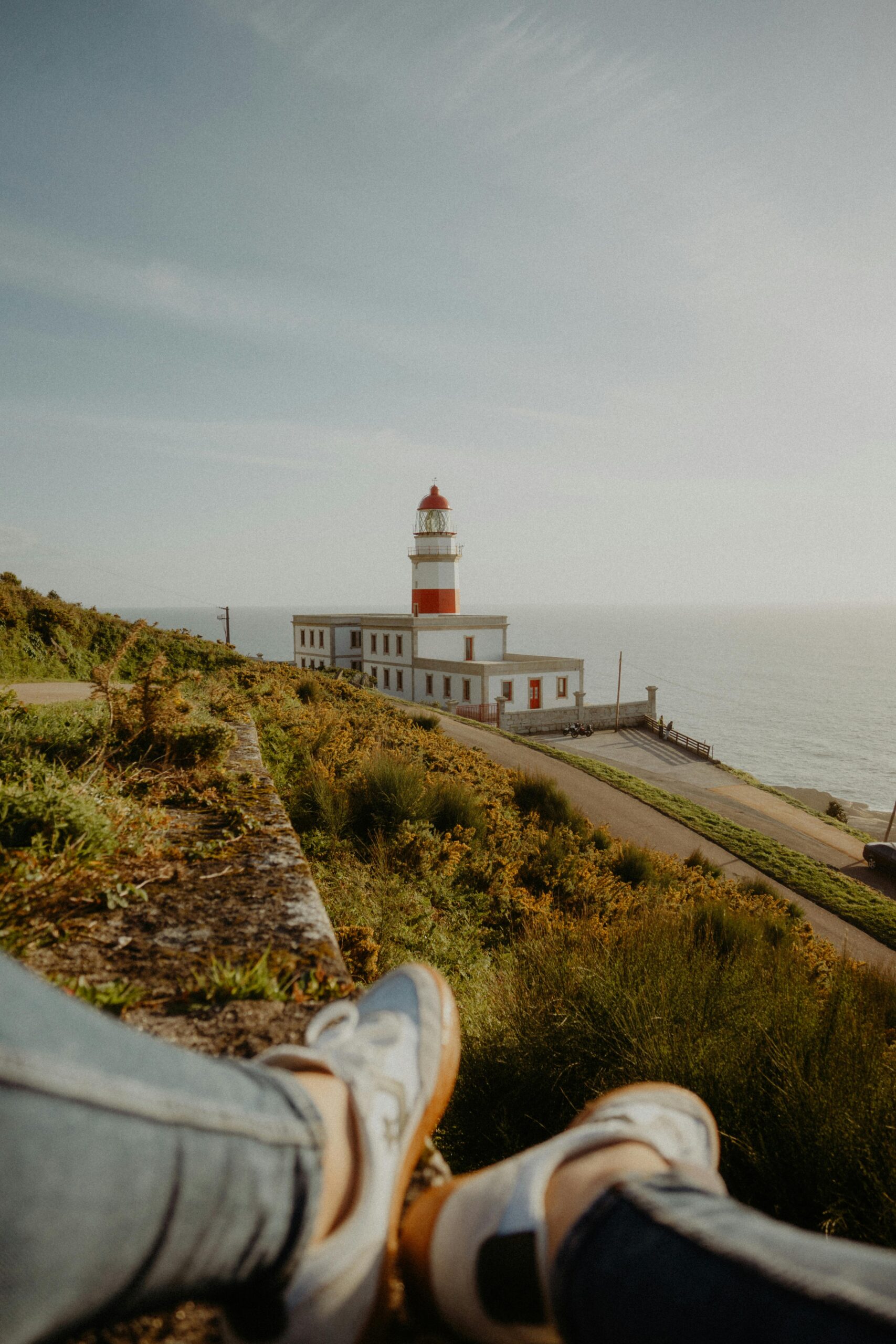 Scenic view of Cape Silleiro Lighthouse with a person relaxing. Perfect for travel enthusiasts.